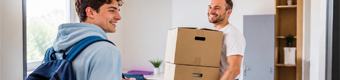 Zwei Studenten tragen Umzugskartons in die neue Wohnung